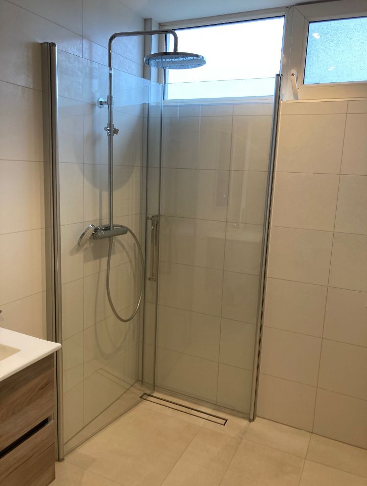 Douche met lichte wandtegels, glazen deur en regendouche